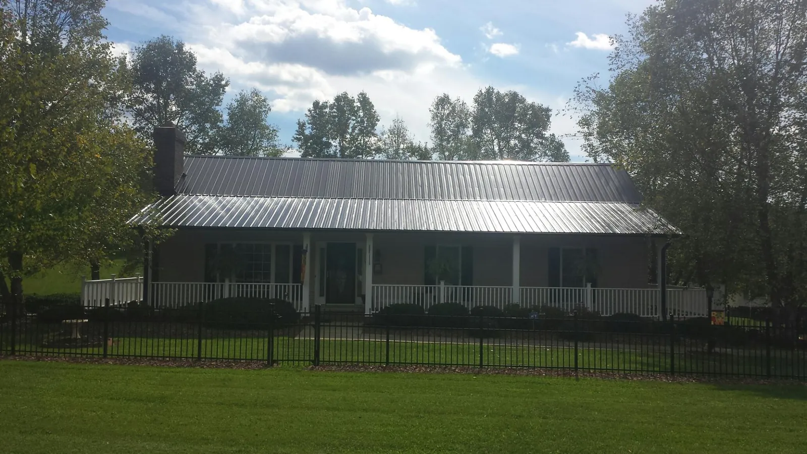 Gray metal roof on a brick ranch with a full width front porch — Gutter Guard Installation work by our crew in Mount Pleasant